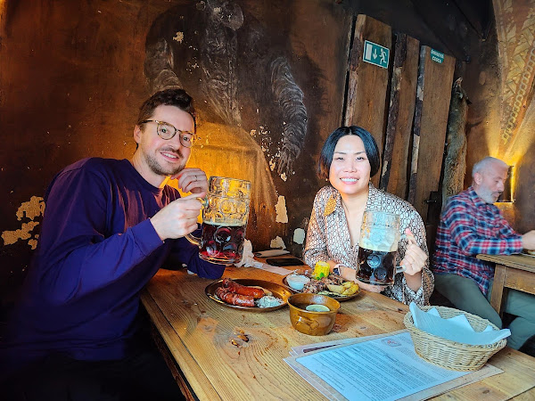 2 people with big beers in an old tavern